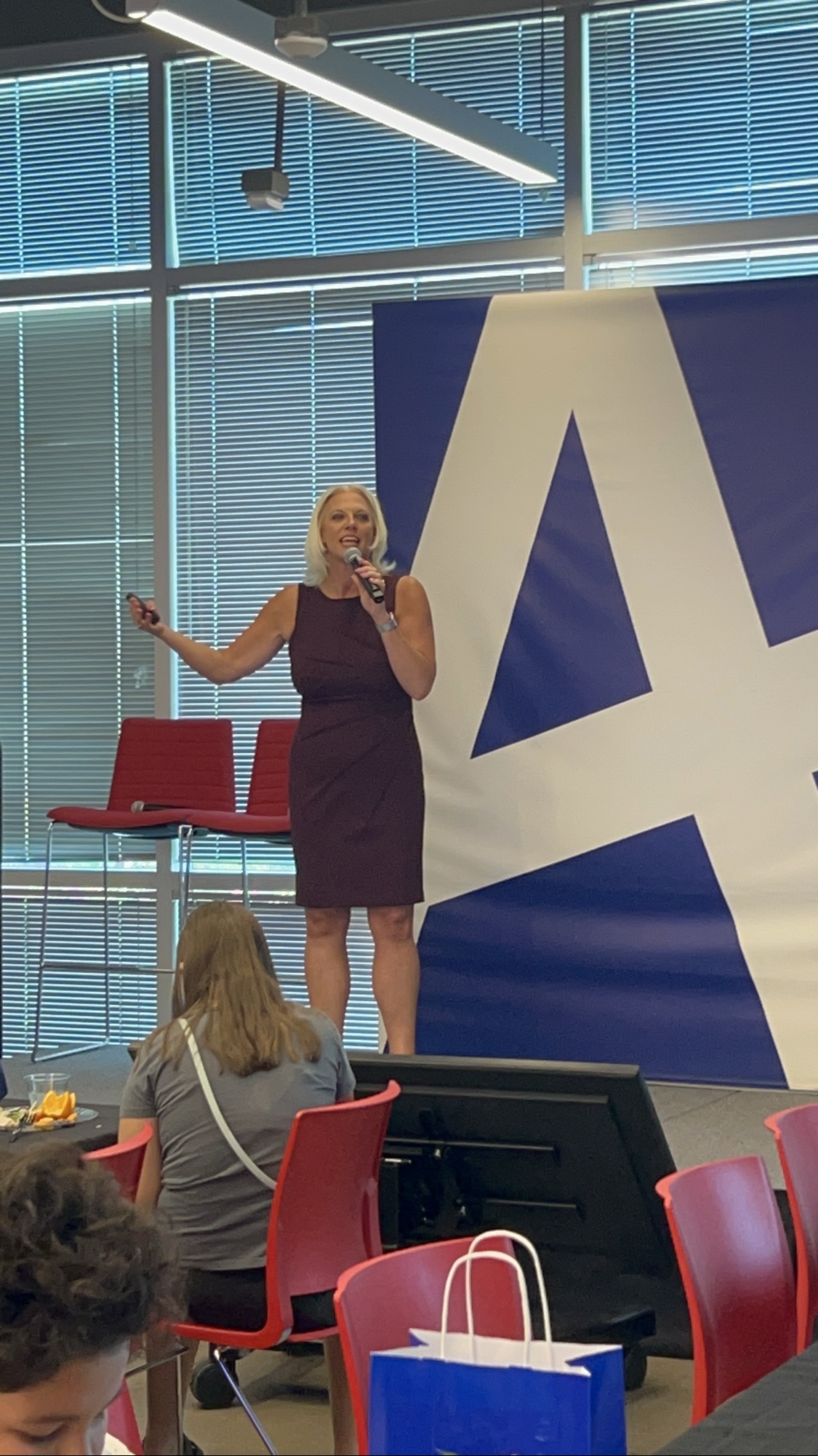 Jessica Pierce on stage with a microphone speaking at the 2025 Inspired LeadHER graduation event.
