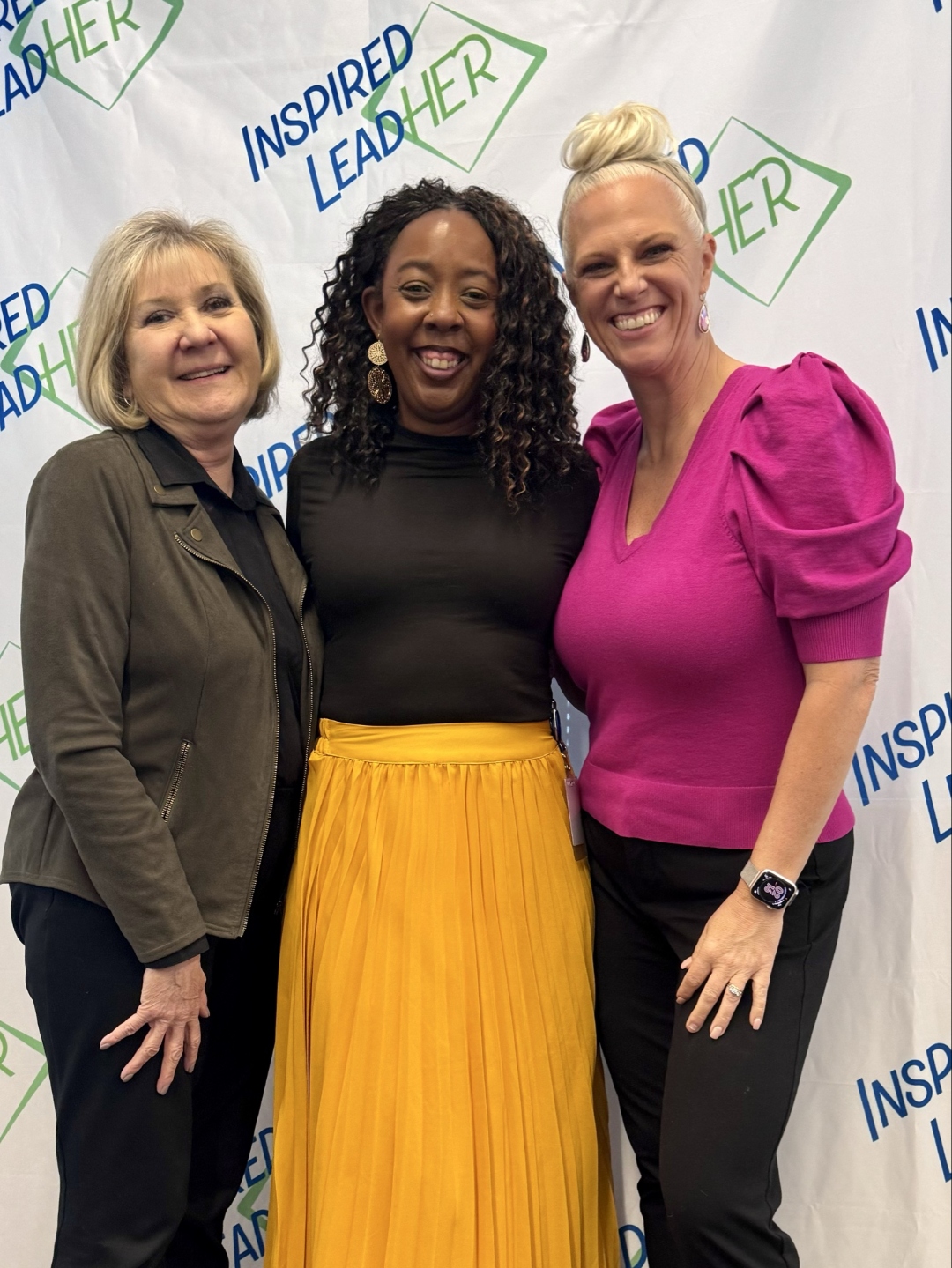 Linda Luman, Brenda Mariah, and Jessica Pierce standing together in front of the Inspired LeadHER backdrop.